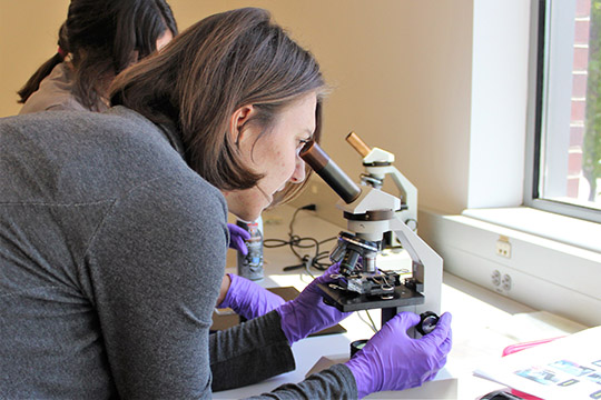 Rachel looks through the microscope to see how her chip is aligned.