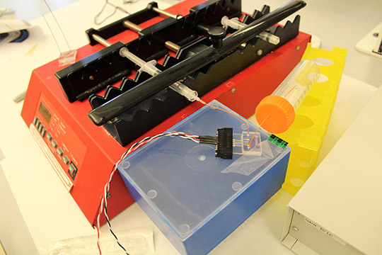 A microfluidic chip connected to the syringe pump and electronics.
