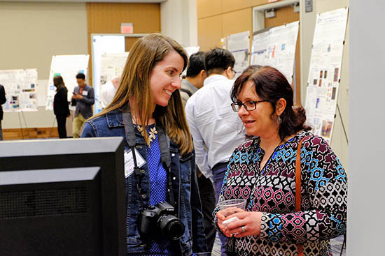 Lindsey Roe, CBM2 Administrative Assistant, visits with Maggie Witek at the All Hands Meeting poster session.