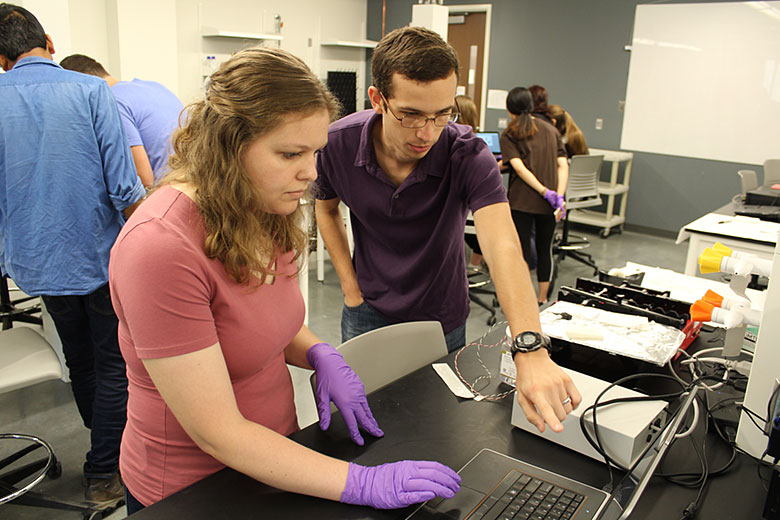 Logan Robart (right) helps Abigail Kreznor (left) with the settings in the computer to run her experiment
