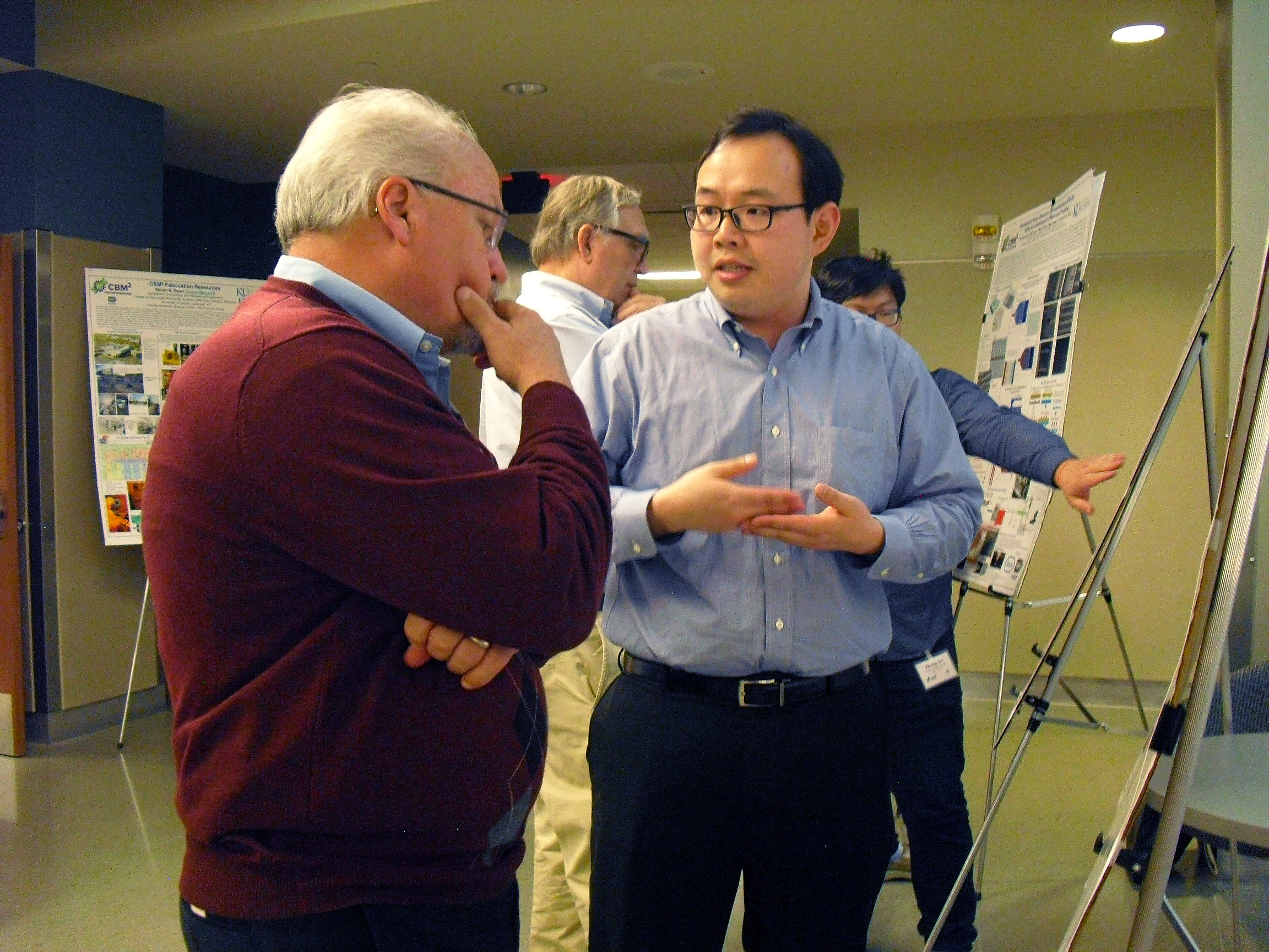 Person explaining research findings on a poster to Dr. Soper, who is attentively listening.