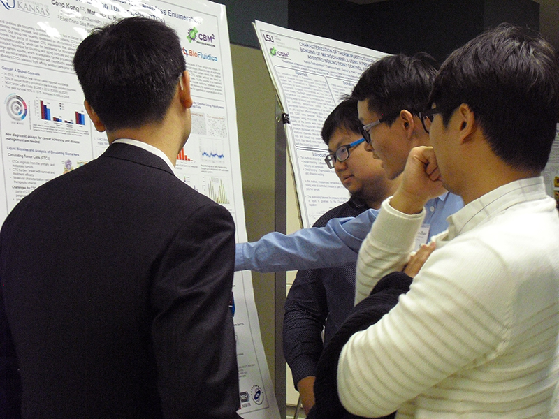 Four individuals gathered in front of a research poster, engaged in discussion.