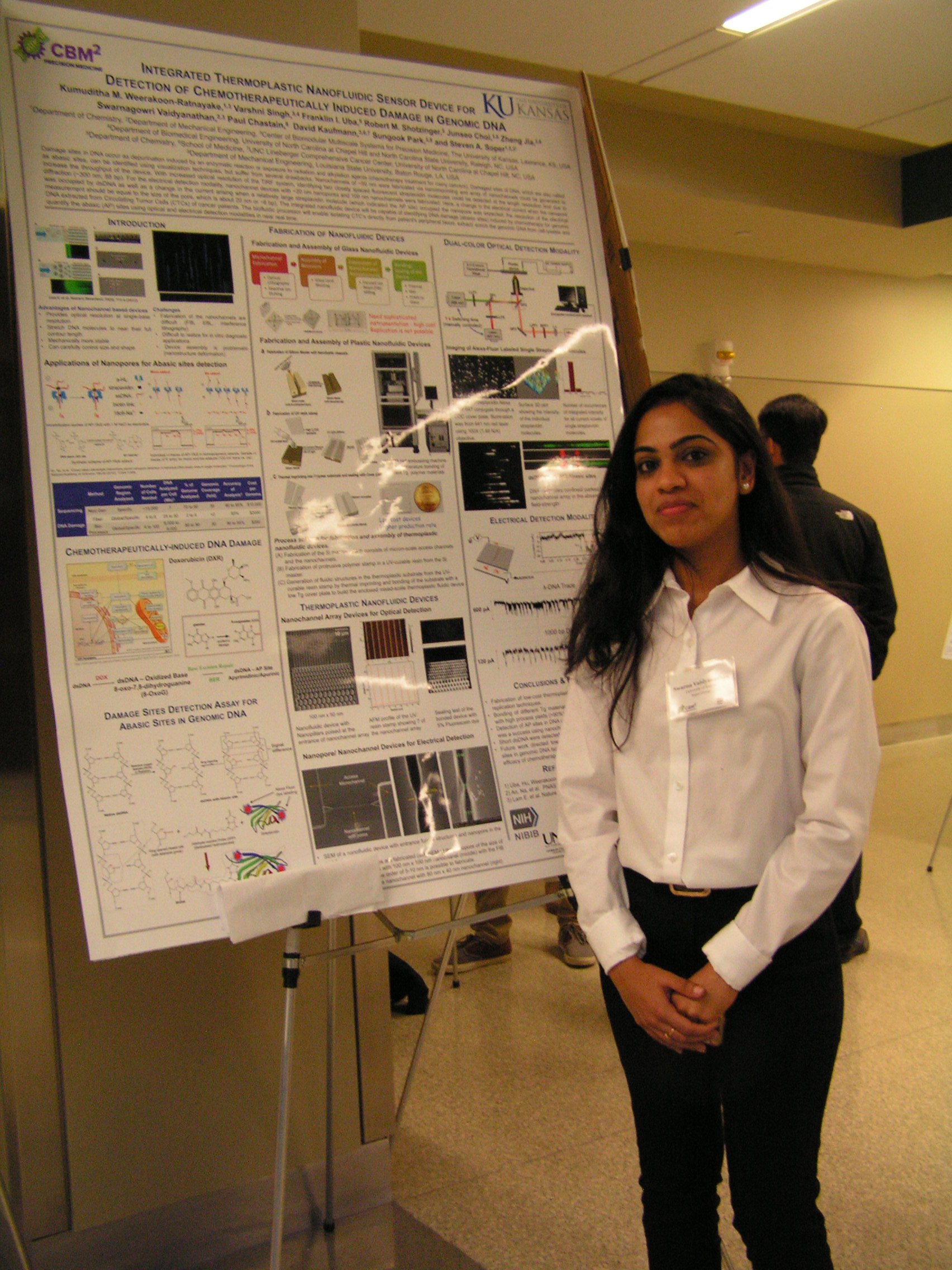 One student standing adjacent to their own research poster.