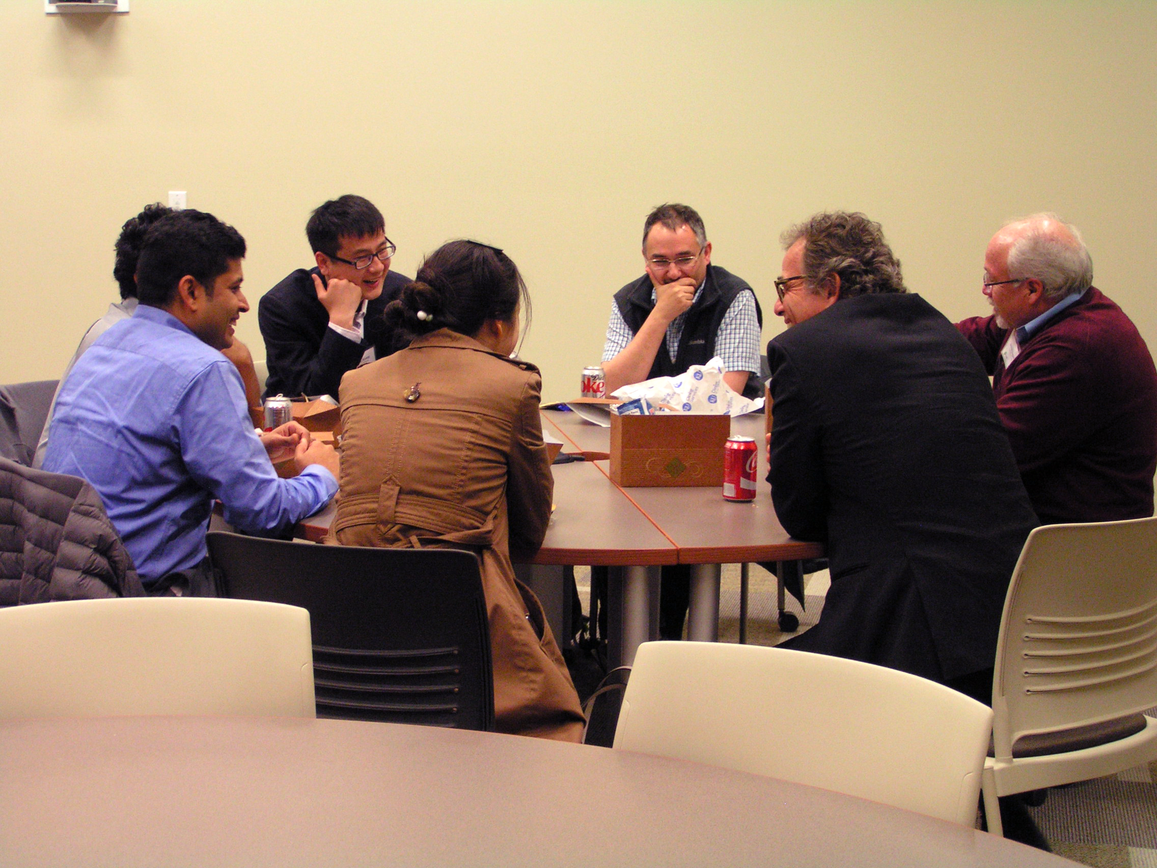 Group of individuals gathered around a table, talking.