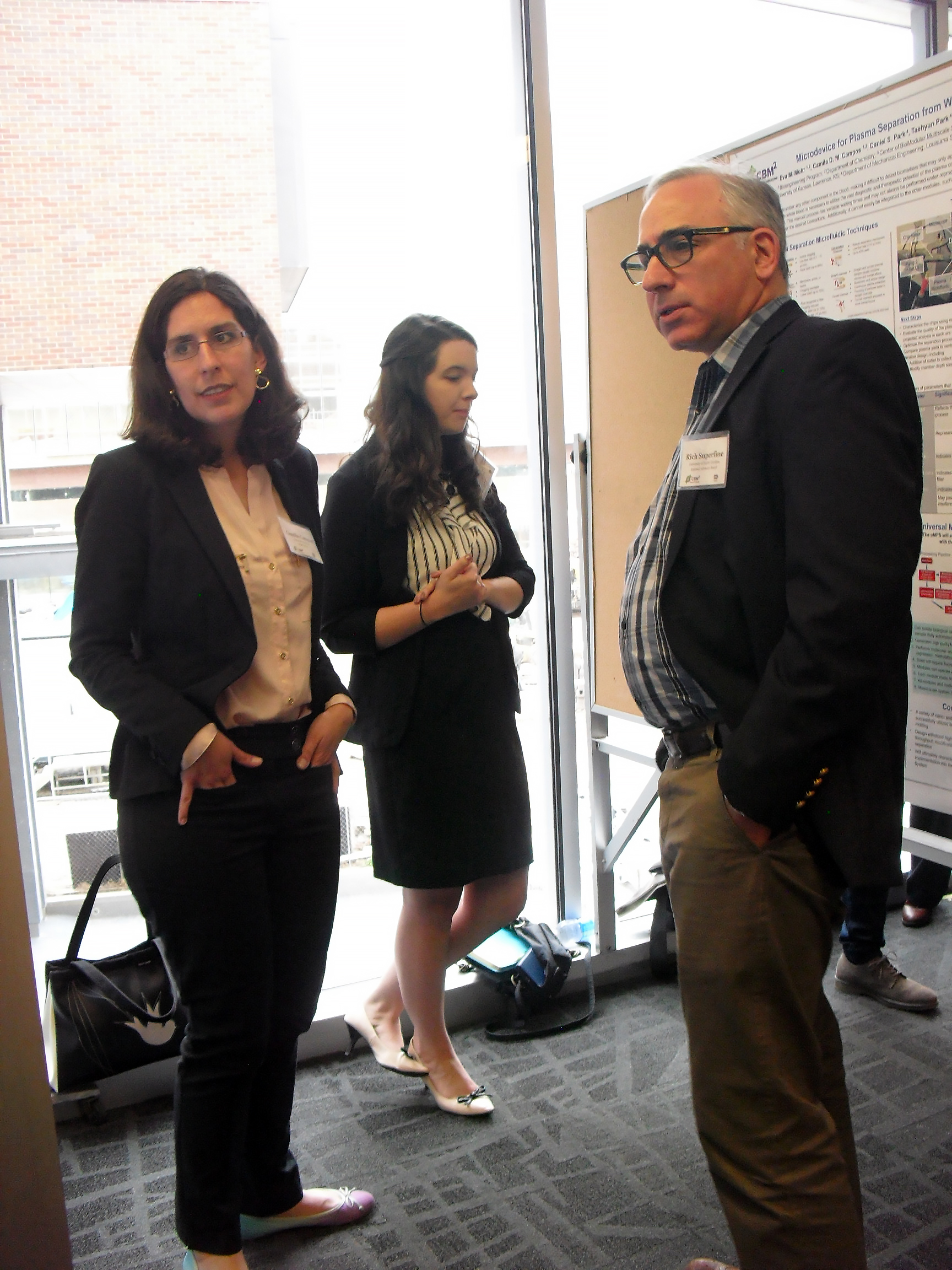 Three people standing in front of a research poster.