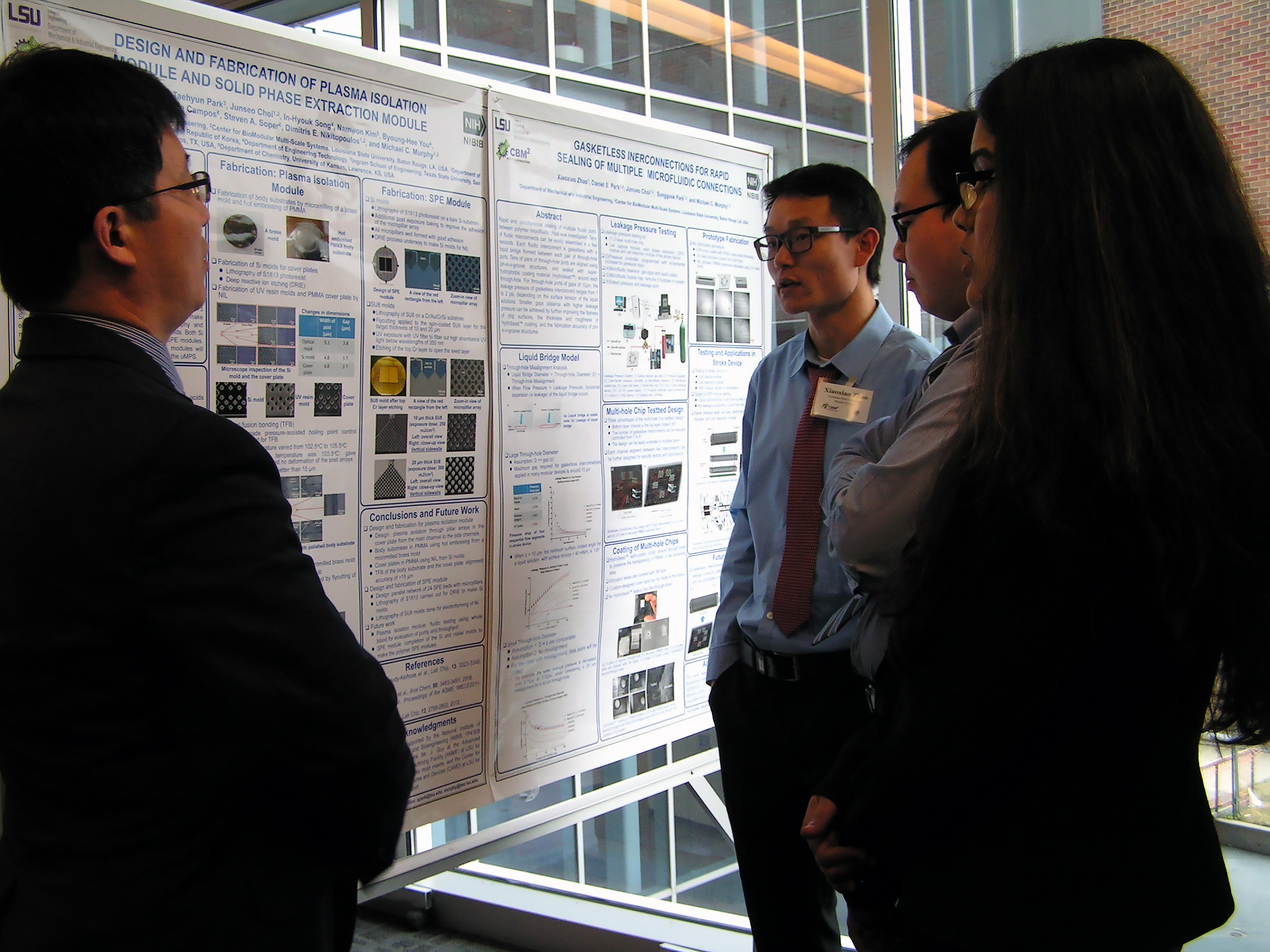 One individual elaborating on a research poster to an audience of three attentive listeners.