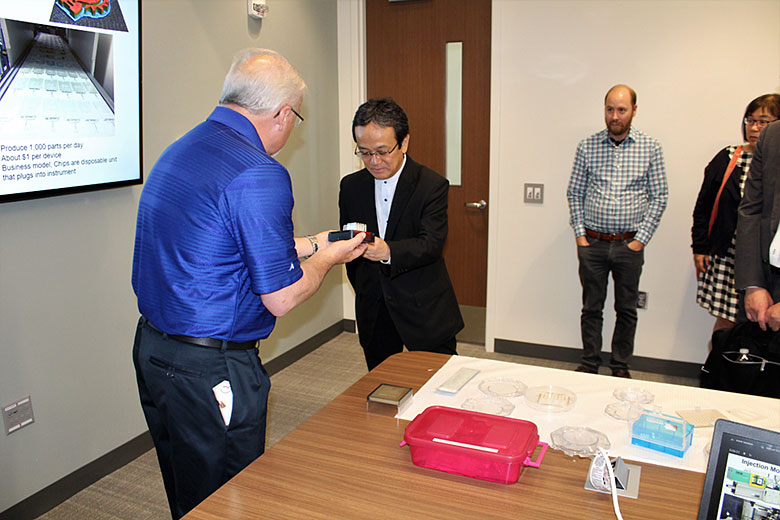 Dr. Soper gives a souvenir microfluidic chip to Dr. Ueda