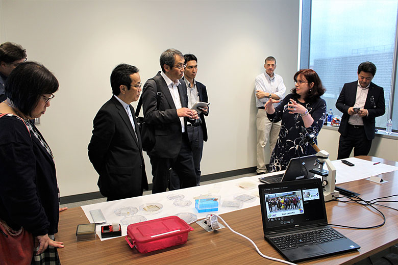 Dr. Ueda, Mr. Kaito, and Mr. Sakamoto listen to a short presentation by Dr. Witek