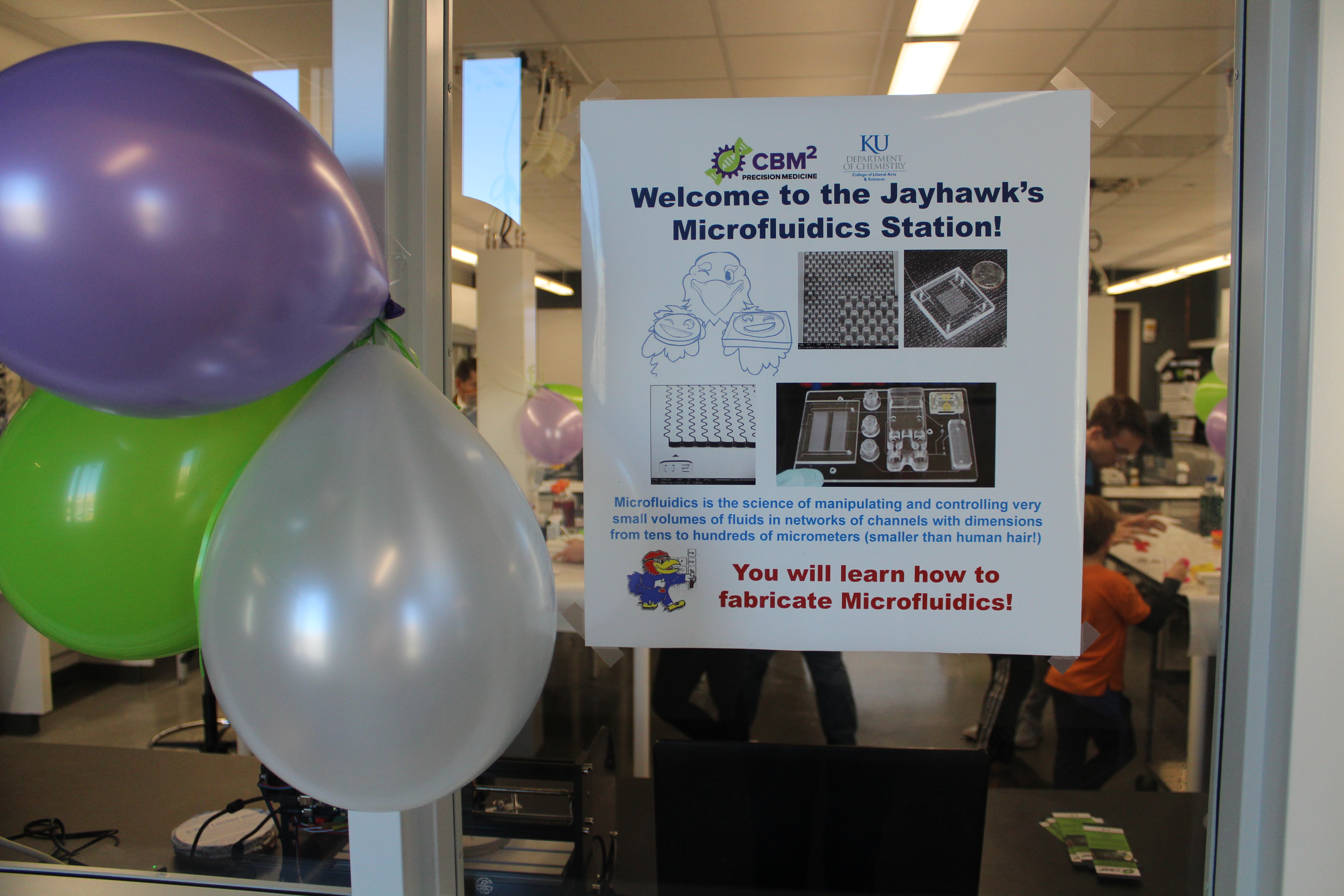 Balloons arranged next to a poster promoting the CBM2's participation in the KU Carnival of Chemistry event, November 2019