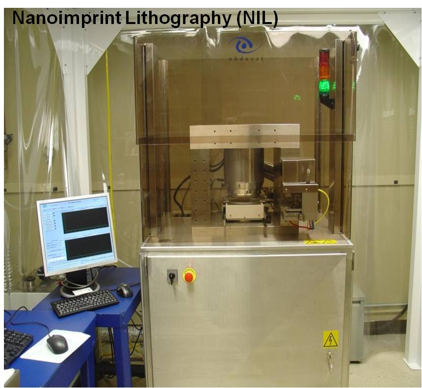 "Nanoimprint Lithography (NIL)" equipment with a clear enclosure, accompanied by a computer monitor on a blue table and a stainless steel control unit with a red button.